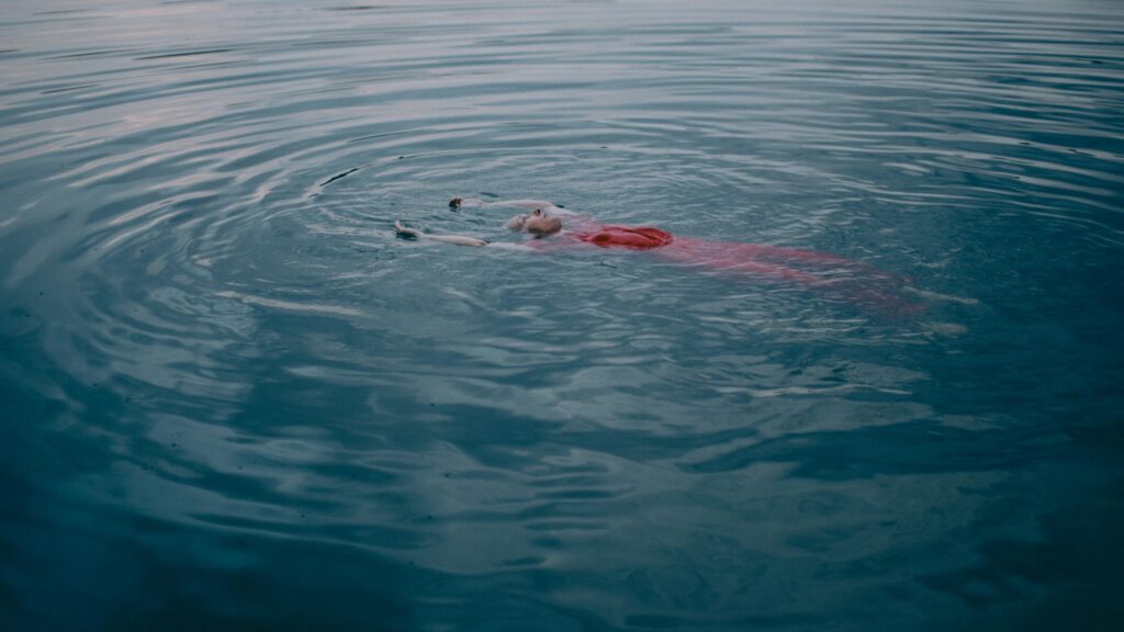 Frau schwimmt in ruhigem Wasser.