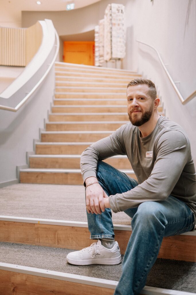 Mann sitzt auf Treppe, lächelt.