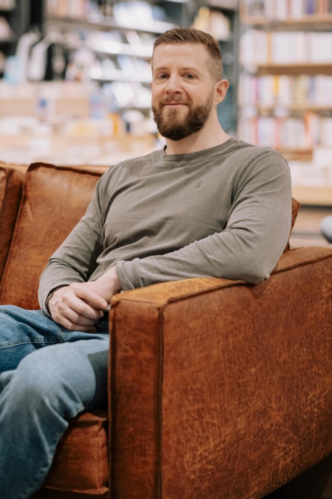 Mann sitzt entspannt auf Sofa.