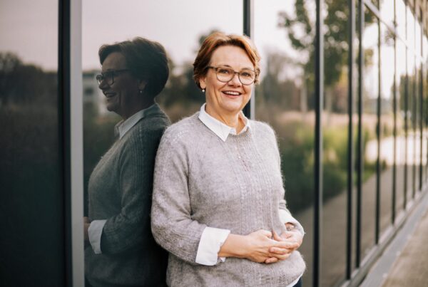 Frau lächelt vor Glaswand.