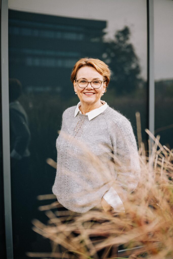 Frau lächelt vor einem Gebäude.