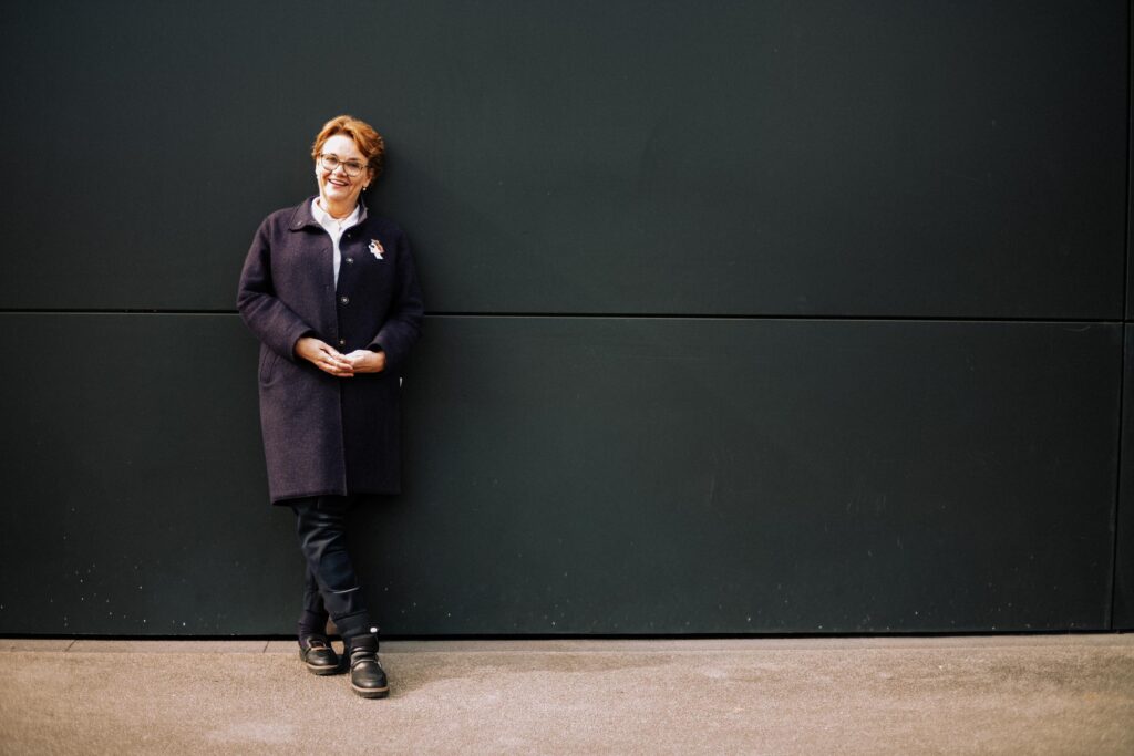 Frau lehnt an einer Wand.